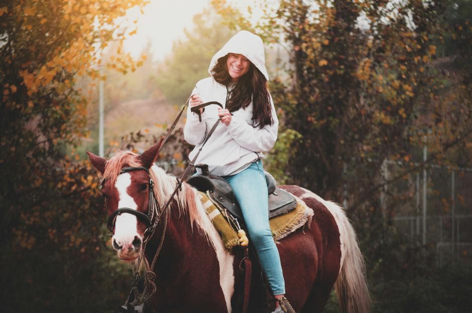 Happy girl riding a horse in autumn